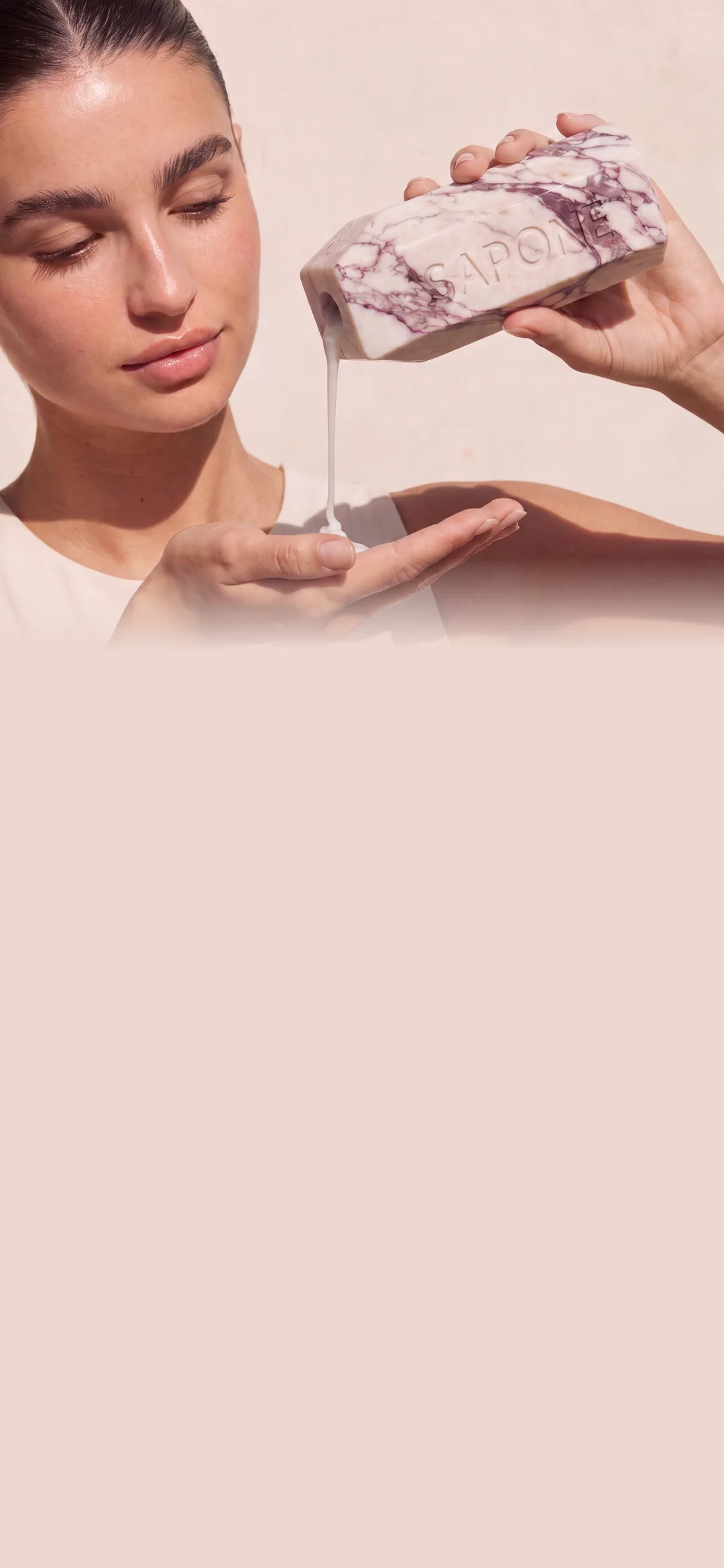 Model pouring shampoo from a marble Sapone bottle into her palm